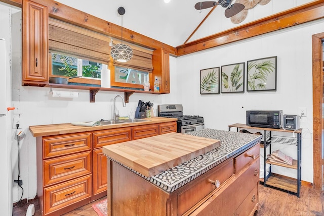 kitchen with light hardwood / wood-style floors, vaulted ceiling, hanging light fixtures, gas range, and ceiling fan