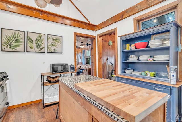 kitchen featuring blue cabinetry, lofted ceiling, gas range, and dark wood-type flooring