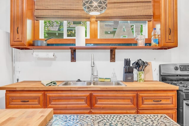 kitchen with wooden counters, sink, a healthy amount of sunlight, and black stove