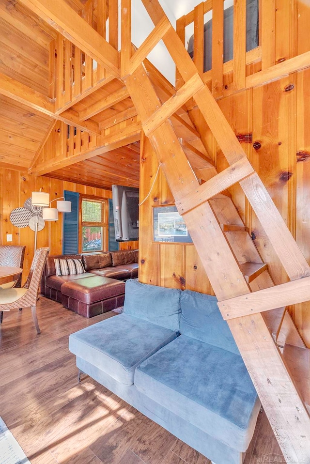 living room featuring lofted ceiling, wood-type flooring, and wood walls