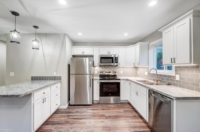 kitchen with hanging light fixtures, light hardwood / wood-style floors, white cabinetry, and stainless steel appliances