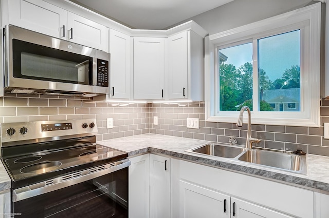 kitchen with decorative backsplash, sink, stainless steel appliances, and white cabinets