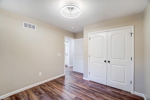 unfurnished bedroom featuring dark hardwood / wood-style flooring and a closet