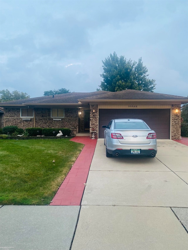 ranch-style house featuring a garage and a front lawn