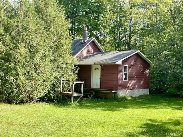156 N Carlshend Rd, Skandia, MI 49885 - view of front of home featuring a front yard, a shingled roof, and a chimney