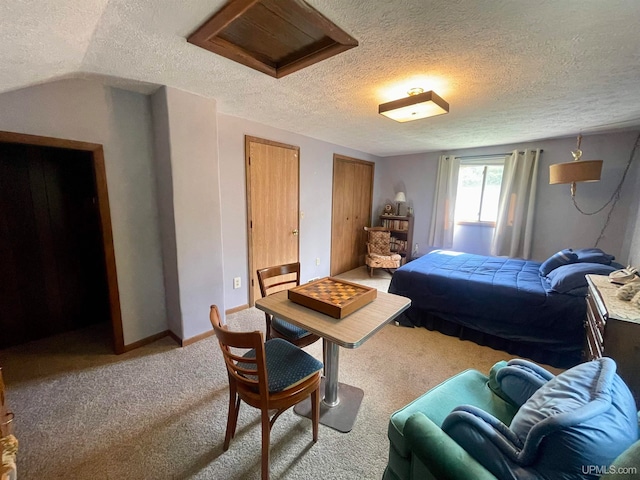 carpeted bedroom featuring a textured ceiling, vaulted ceiling, and two closets