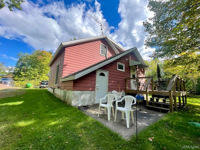 view of property exterior with a lawn, a patio area, and a deck