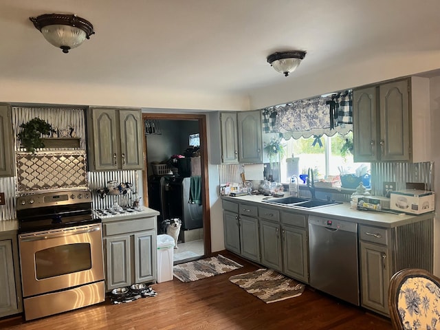 kitchen with gray cabinets, dark hardwood / wood-style floors, tasteful backsplash, sink, and appliances with stainless steel finishes