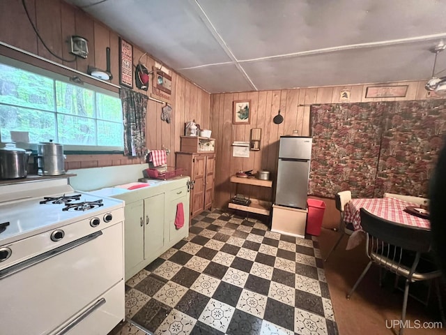 kitchen with white range, stainless steel fridge, and wooden walls