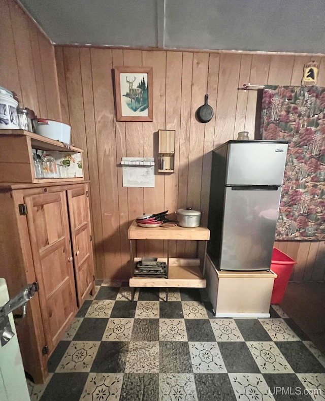 kitchen featuring wooden walls and stainless steel refrigerator