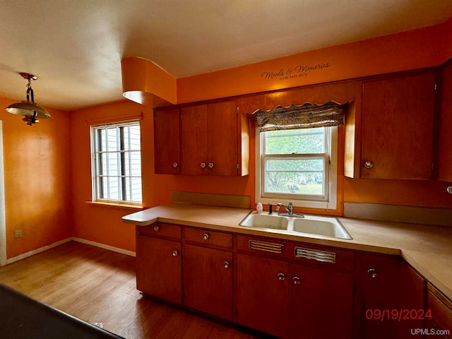 kitchen with hanging light fixtures, sink, and wood-type flooring