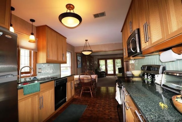 kitchen with sink, decorative light fixtures, appliances with stainless steel finishes, dark parquet flooring, and dark stone countertops