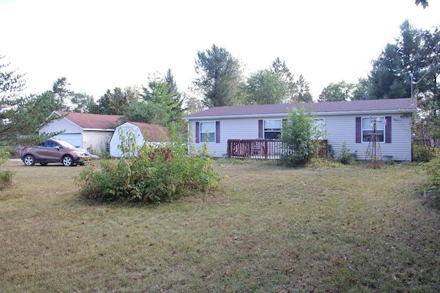 view of front facade featuring a storage shed, a deck, and a front lawn