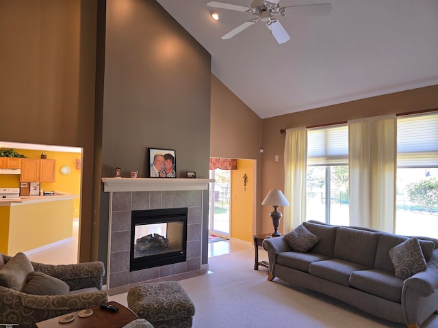 living room with high vaulted ceiling, ceiling fan, and a tile fireplace