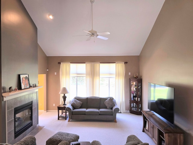 carpeted living room featuring ceiling fan, a tiled fireplace, and high vaulted ceiling