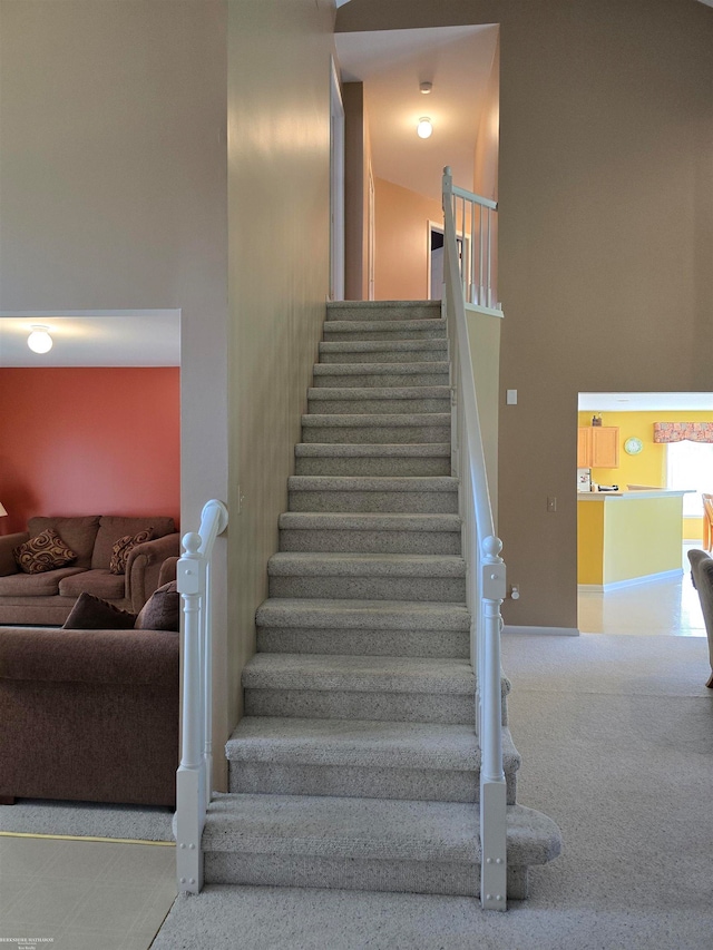 stairway featuring carpet flooring and a towering ceiling