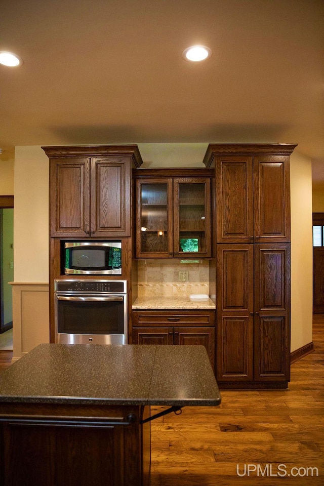 kitchen featuring dark brown cabinets, a breakfast bar, dark hardwood / wood-style floors, tasteful backsplash, and appliances with stainless steel finishes