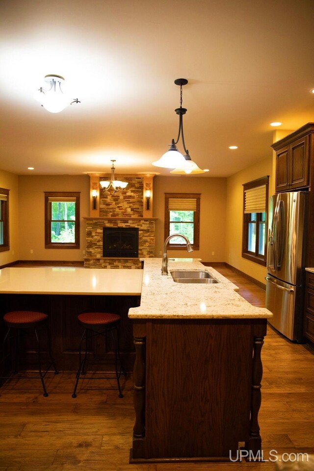 kitchen with pendant lighting, dark wood-type flooring, stainless steel fridge, and sink