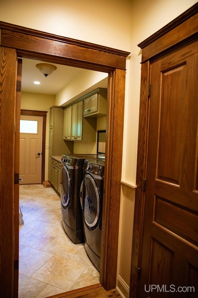 clothes washing area with washer and clothes dryer and cabinets