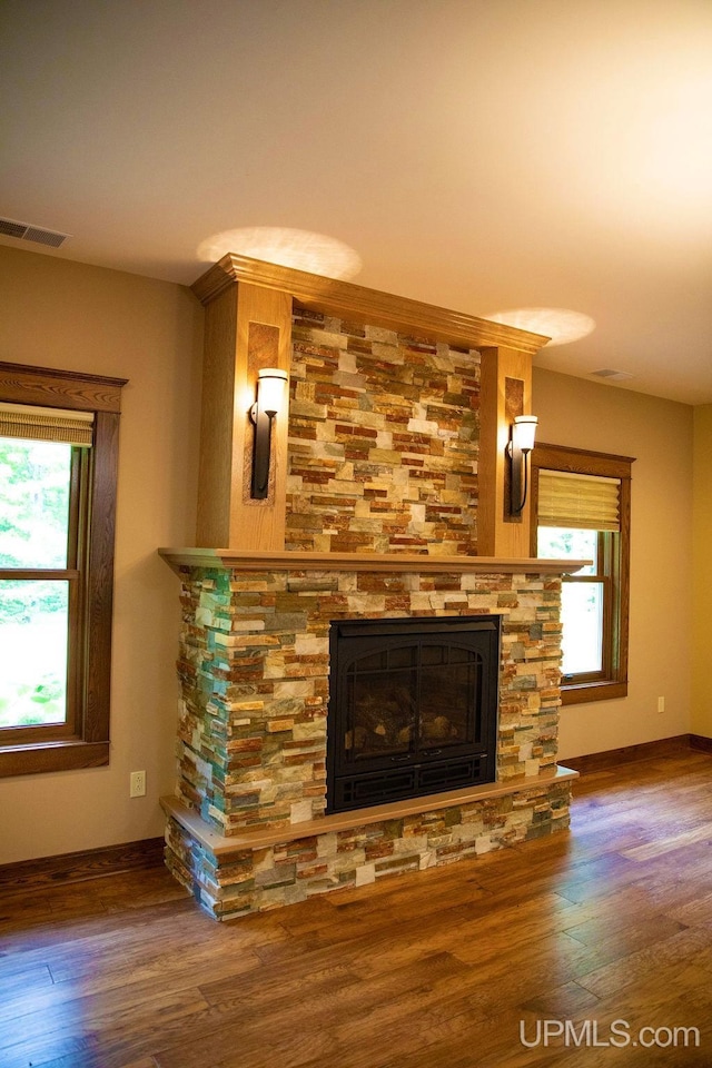 unfurnished living room with wood-type flooring, a fireplace, and plenty of natural light