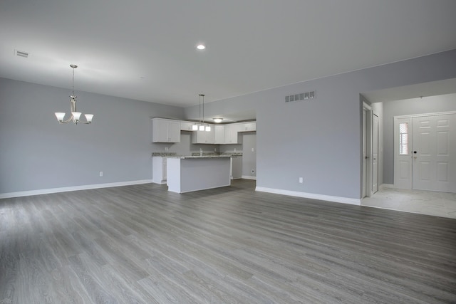 unfurnished living room with a chandelier and light hardwood / wood-style floors