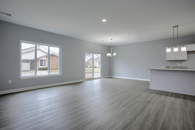 unfurnished living room featuring a notable chandelier and dark hardwood / wood-style floors