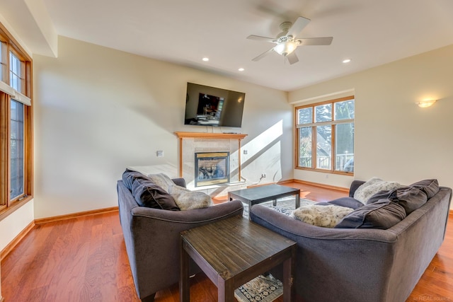 living room featuring ceiling fan, a tiled fireplace, and hardwood / wood-style floors