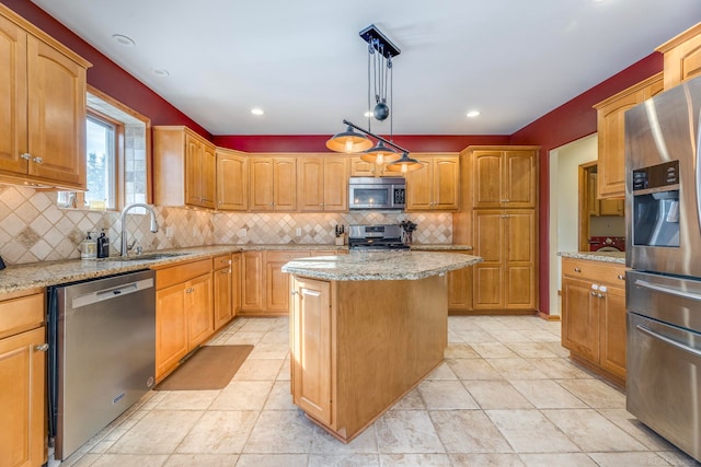 kitchen featuring appliances with stainless steel finishes, light stone counters, a center island, decorative light fixtures, and sink