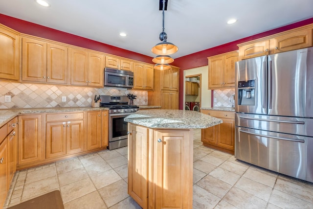 kitchen with appliances with stainless steel finishes, decorative backsplash, a kitchen island, and light stone counters