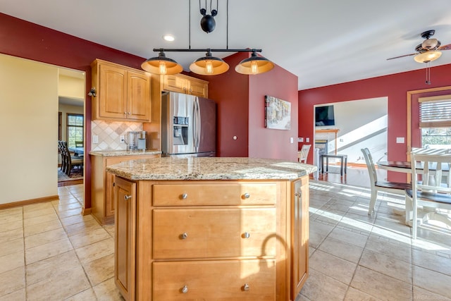 kitchen with pendant lighting, a center island, stainless steel fridge with ice dispenser, decorative backsplash, and ceiling fan