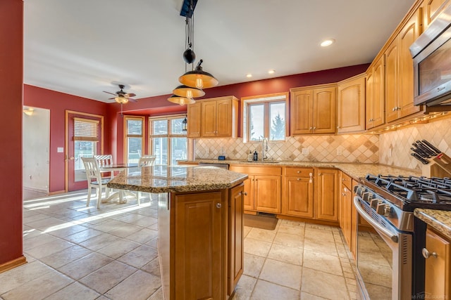 kitchen featuring ceiling fan, pendant lighting, a kitchen island, backsplash, and appliances with stainless steel finishes