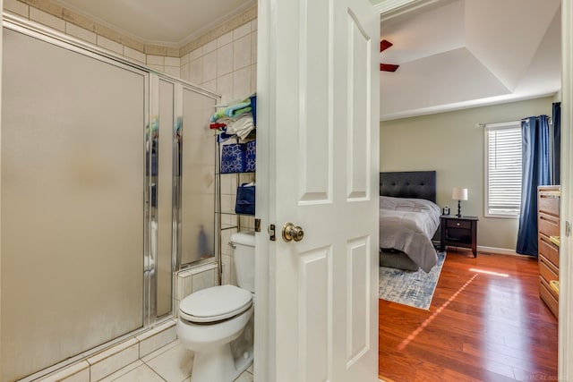 bathroom with hardwood / wood-style flooring, a shower with shower door, toilet, and crown molding