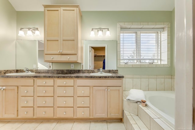 bathroom featuring tiled bath, vanity, and tile patterned flooring