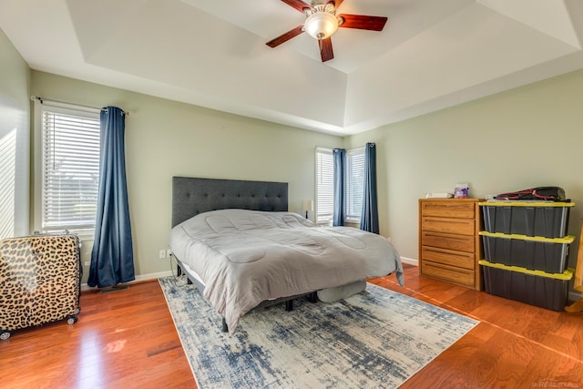 bedroom featuring wood-type flooring, a tray ceiling, and ceiling fan