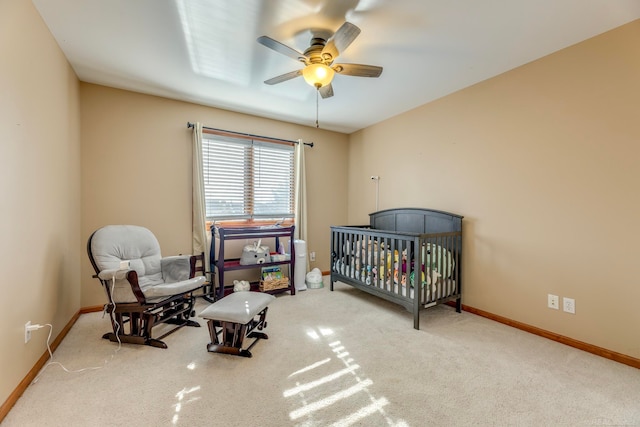 bedroom featuring a crib, light carpet, and ceiling fan