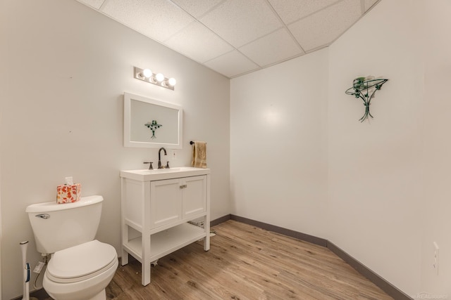 bathroom with vanity, hardwood / wood-style flooring, a paneled ceiling, and toilet