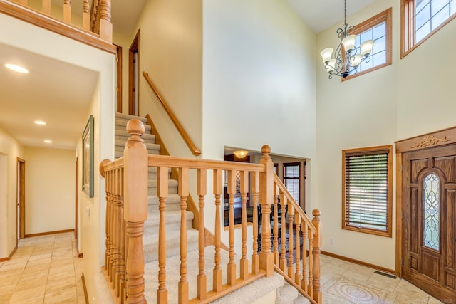 entrance foyer featuring a notable chandelier, a towering ceiling, and light tile patterned floors