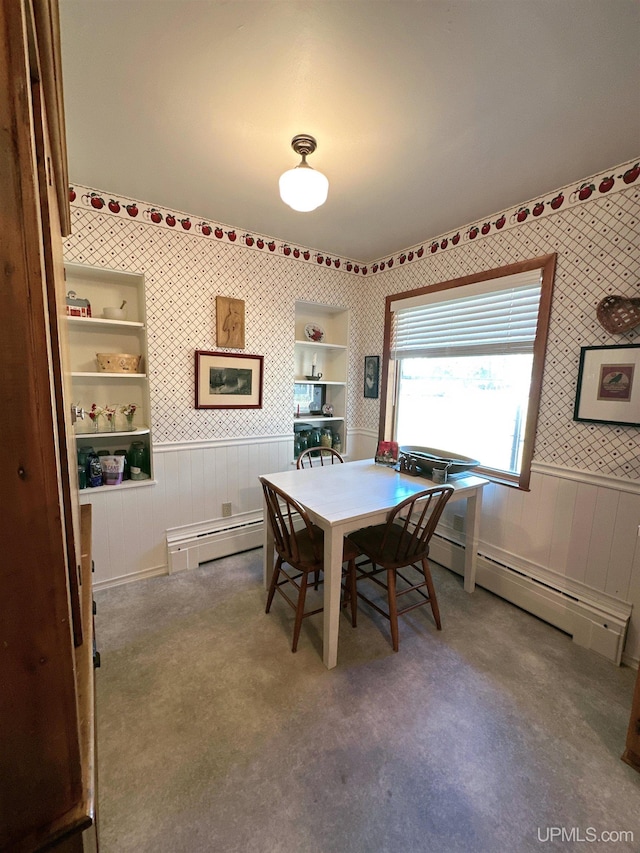 dining space featuring wood walls and a baseboard heating unit