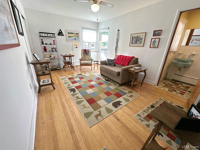 living room featuring light hardwood / wood-style flooring, ceiling fan, and baseboard heating