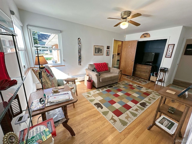 living room featuring ceiling fan, a baseboard radiator, and light wood-type flooring