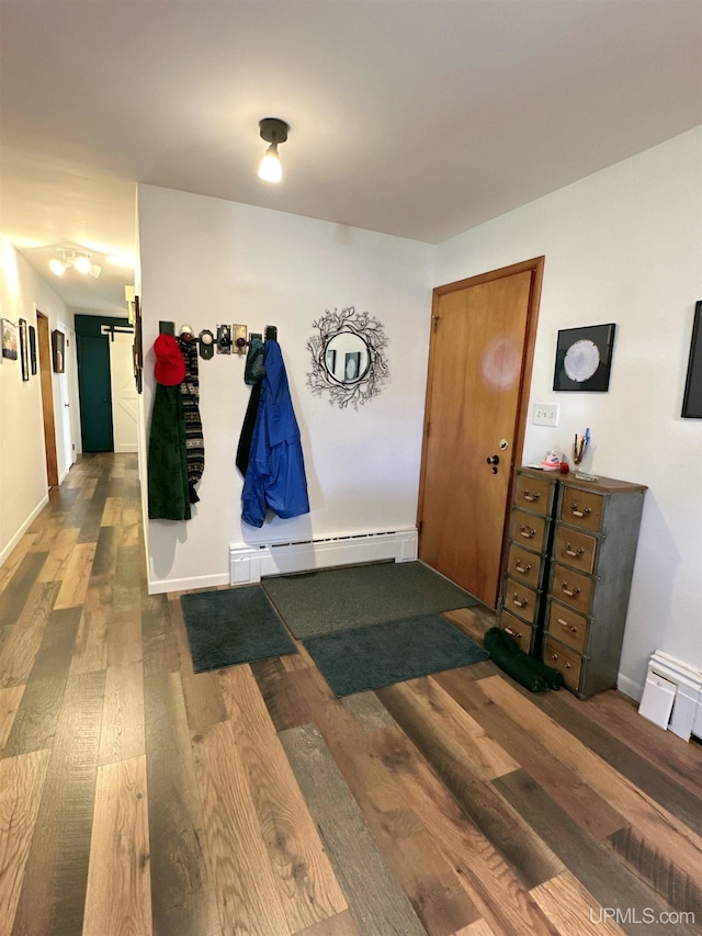 corridor with baseboard heating, hardwood / wood-style floors, and a barn door