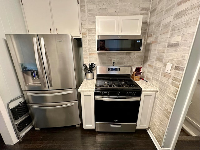 kitchen with white cabinetry, appliances with stainless steel finishes, light stone counters, and dark hardwood / wood-style flooring