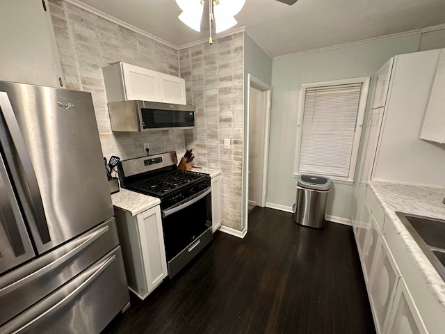 kitchen with dark hardwood / wood-style floors, white cabinetry, appliances with stainless steel finishes, ornamental molding, and ceiling fan