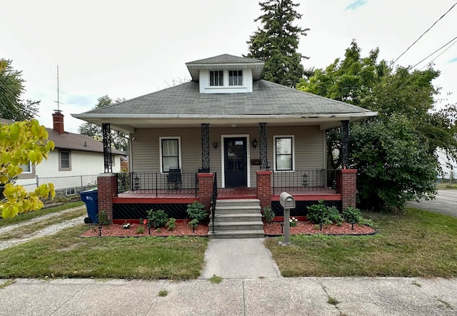 bungalow-style home featuring covered porch and a front yard