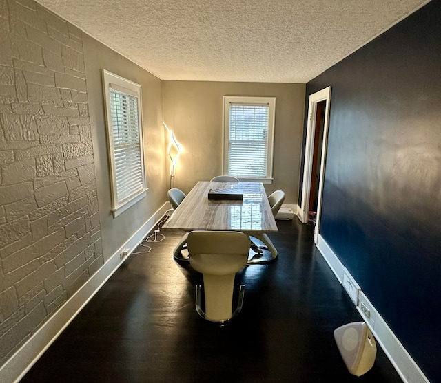 dining space with a textured ceiling and dark hardwood / wood-style flooring