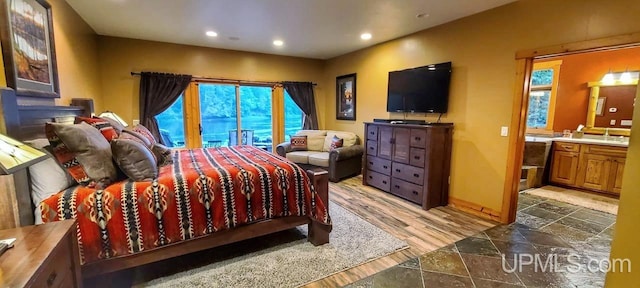 bedroom featuring ensuite bathroom, hardwood / wood-style flooring, access to exterior, and multiple windows