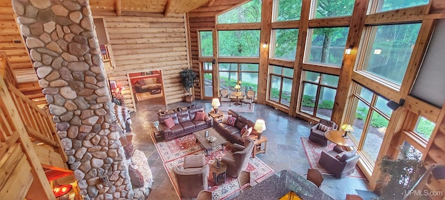 unfurnished living room featuring beamed ceiling, high vaulted ceiling, rustic walls, and plenty of natural light