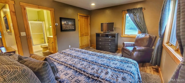 bedroom featuring wood-type flooring, a closet, and ensuite bath