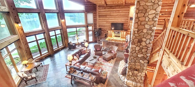 living room featuring log walls, dark wood-type flooring, high vaulted ceiling, and a wealth of natural light