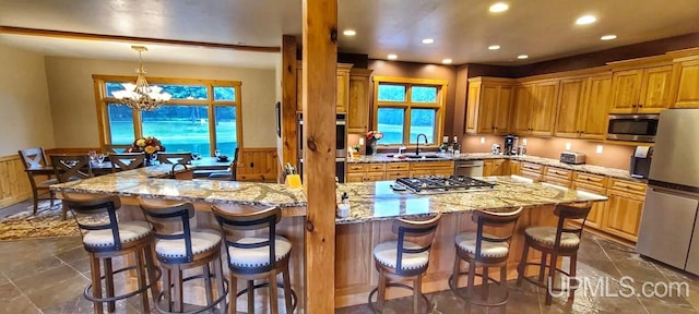 kitchen with sink, a kitchen island, decorative light fixtures, a chandelier, and appliances with stainless steel finishes